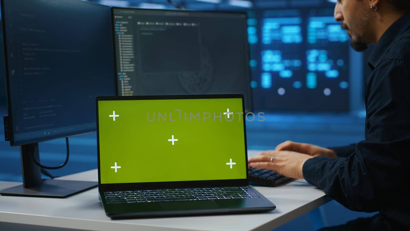 Close up shot of mockup laptop on desk next to IT developer typing at PC by DCStudio