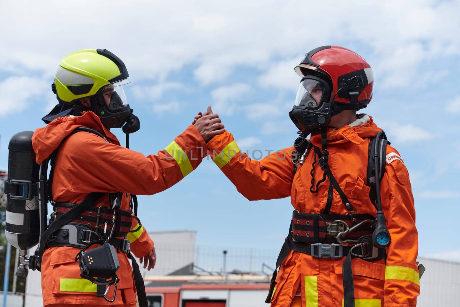 A unified team of firefighters, adorned in their uniforms, engages in a heartfelt celebration marked by triumphant salutes and cheers, embodying the joy and gratitude following the successful completion of a challenging firefighting mission.