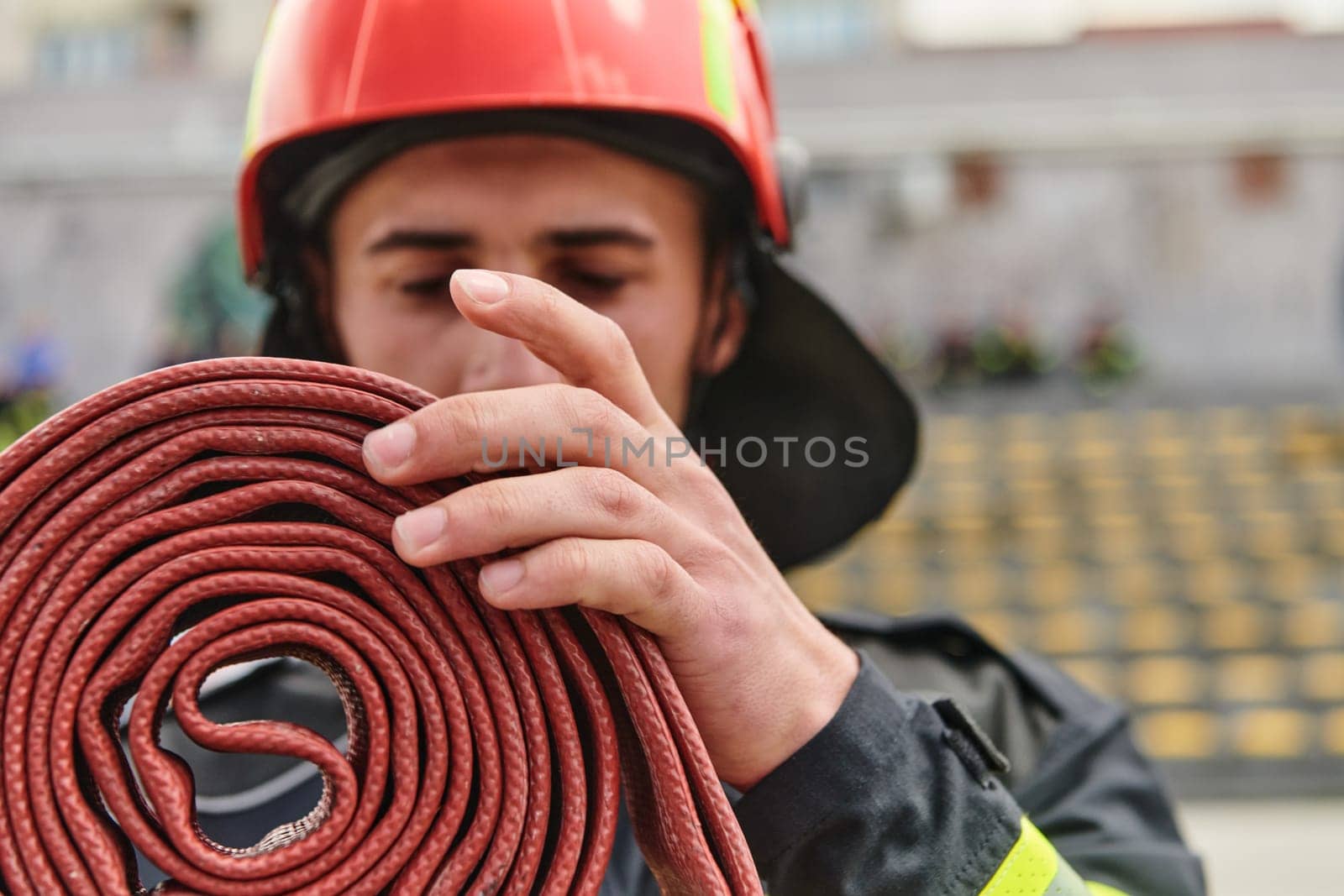 A dedicated firefighter meticulously coils the fire hose after successfully extinguishing a blaze, showcasing the critical post-incident responsibilities.