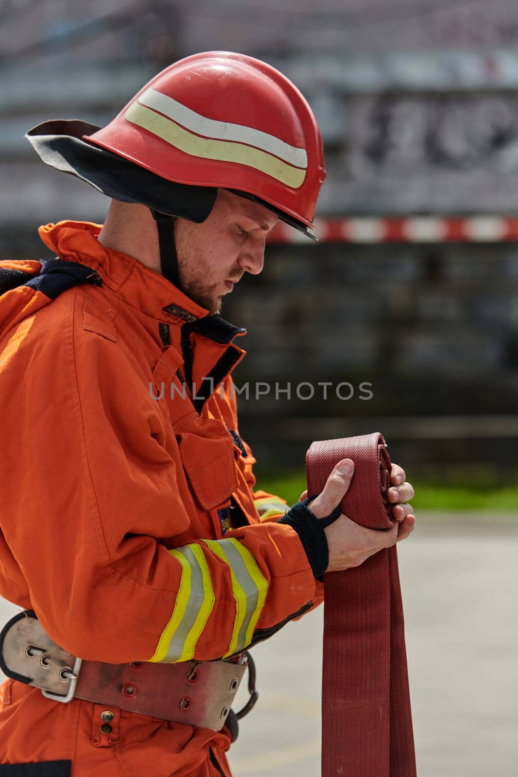 A dedicated firefighter meticulously coils the fire hose after successfully extinguishing a blaze, showcasing the critical post-incident responsibilities.