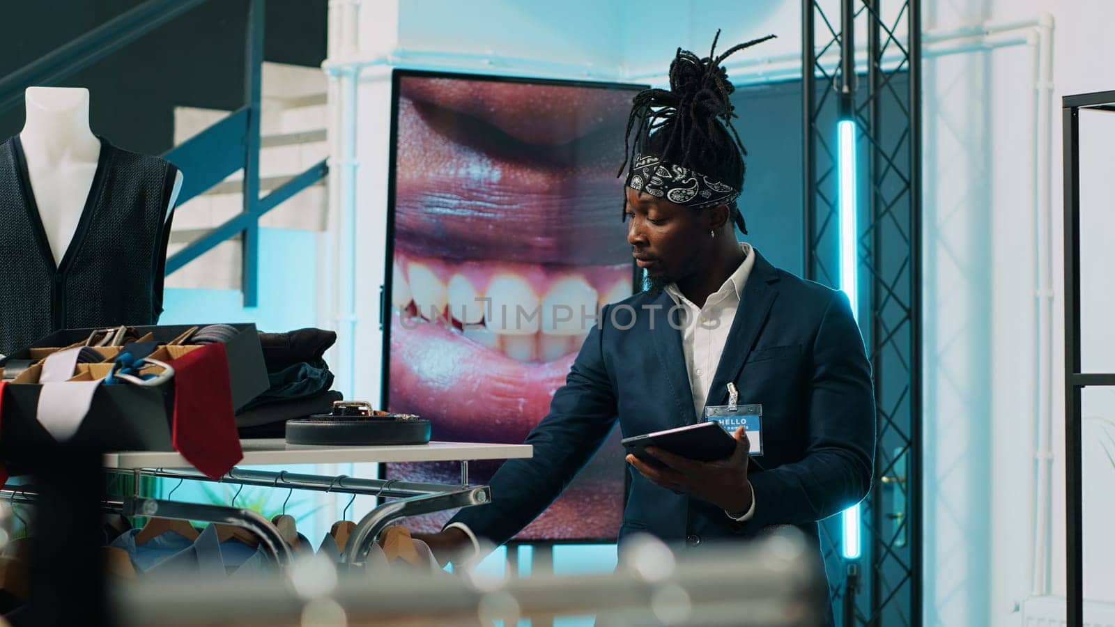 Retail clerk working at a fashion boutique to offer styling advice to shoppers, helping senior man to find trendy clothing. African american employee assisting client in buying shirts. Camera A.