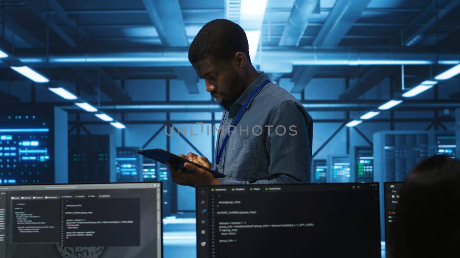 Manager uses tablet, supervising team programming servers providing computing resources for different workloads. Inspector using device to oversee engineers in data center mending supercomputers
