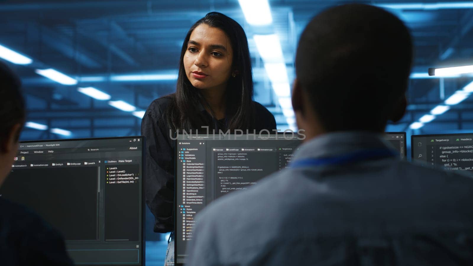 Manager in data center talking with employees about annual system review after checking parameters on laptop. Supervisor overseeing server clusters discussing with multiethnic team