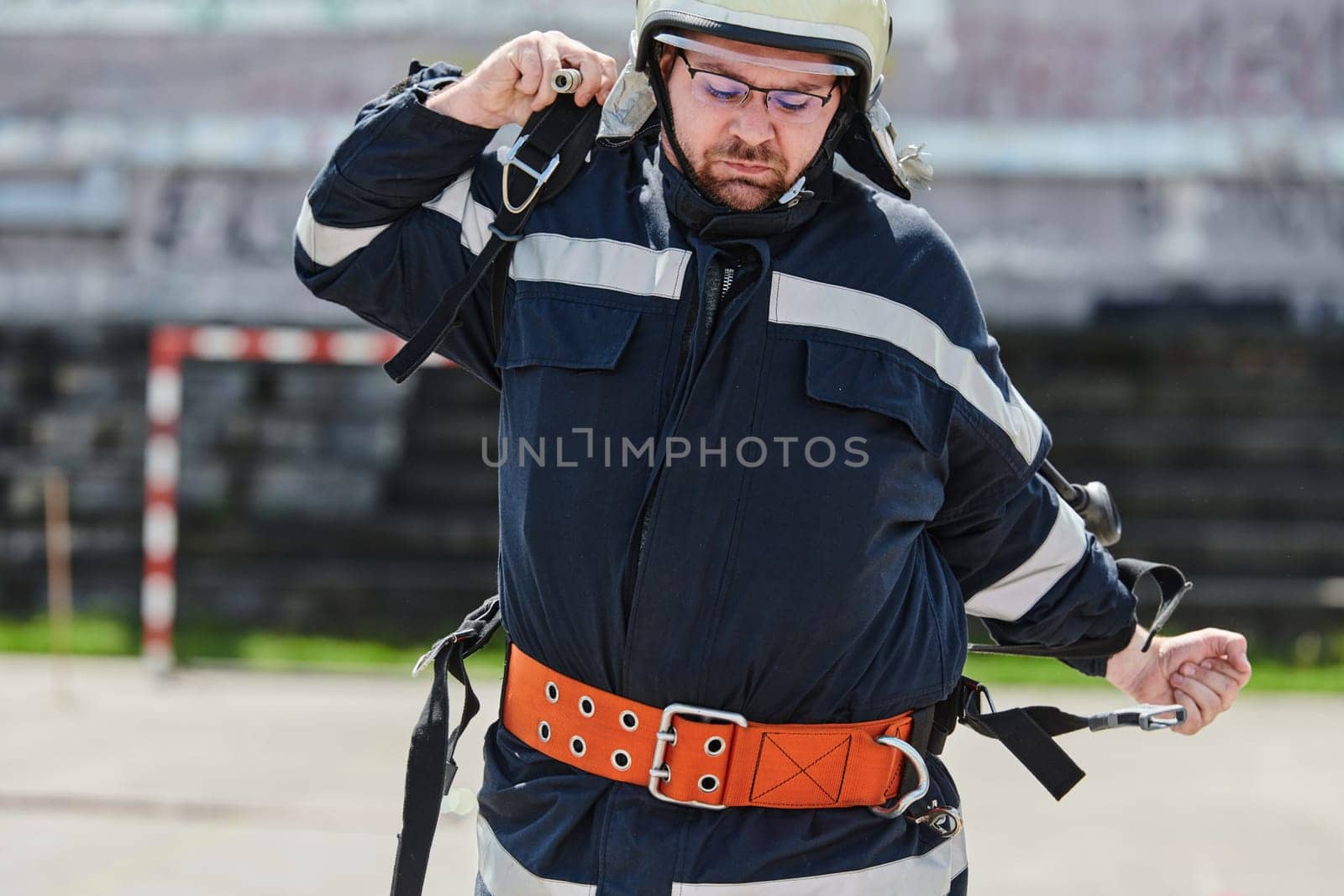 A firefighter dons the essential components of their professional gear, embodying resilience, commitment, and readiness as they gear up for a hazardous firefighting mission, a testament to their unwavering dedication to protecting and saving lives.