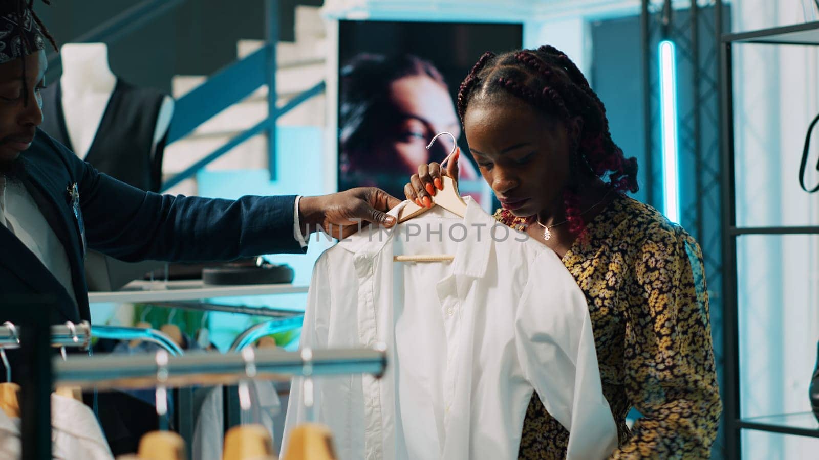 African american shopper looking for pregnancy clothing items, shopping session at department store. Employee offering suggestions for pregnant client, trendy designer brands. Camera A.
