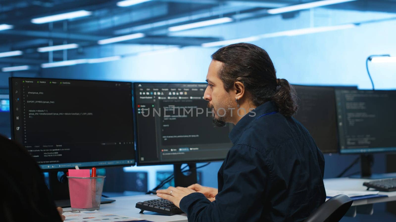 Knowledgeable engineer upgrading equipment in data center, zoom in shot. Specialist at PC desk in high tech establishment overseeing server rows, typing on keyboard, close up shot