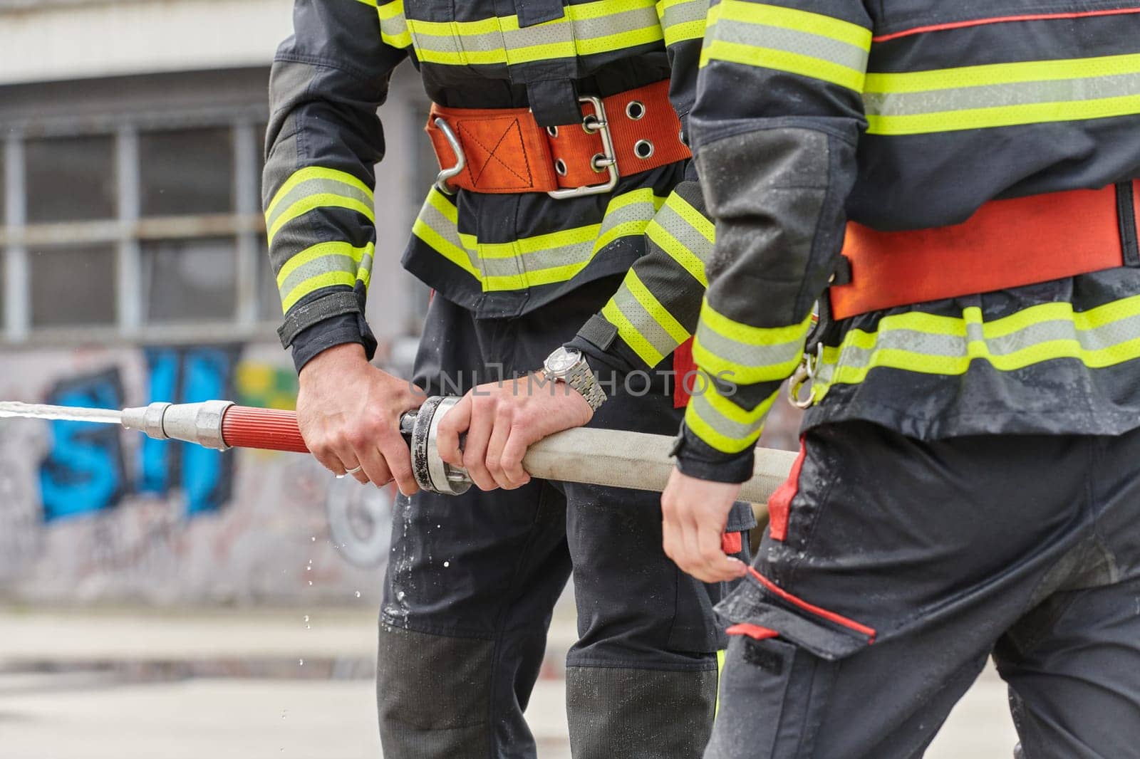 In a dynamic display of synchronized teamwork, firefighters hustle to carry, connect, and deploy firefighting hoses with precision, showcasing their intensive training and readiness for challenging and high-risk situations ahead.