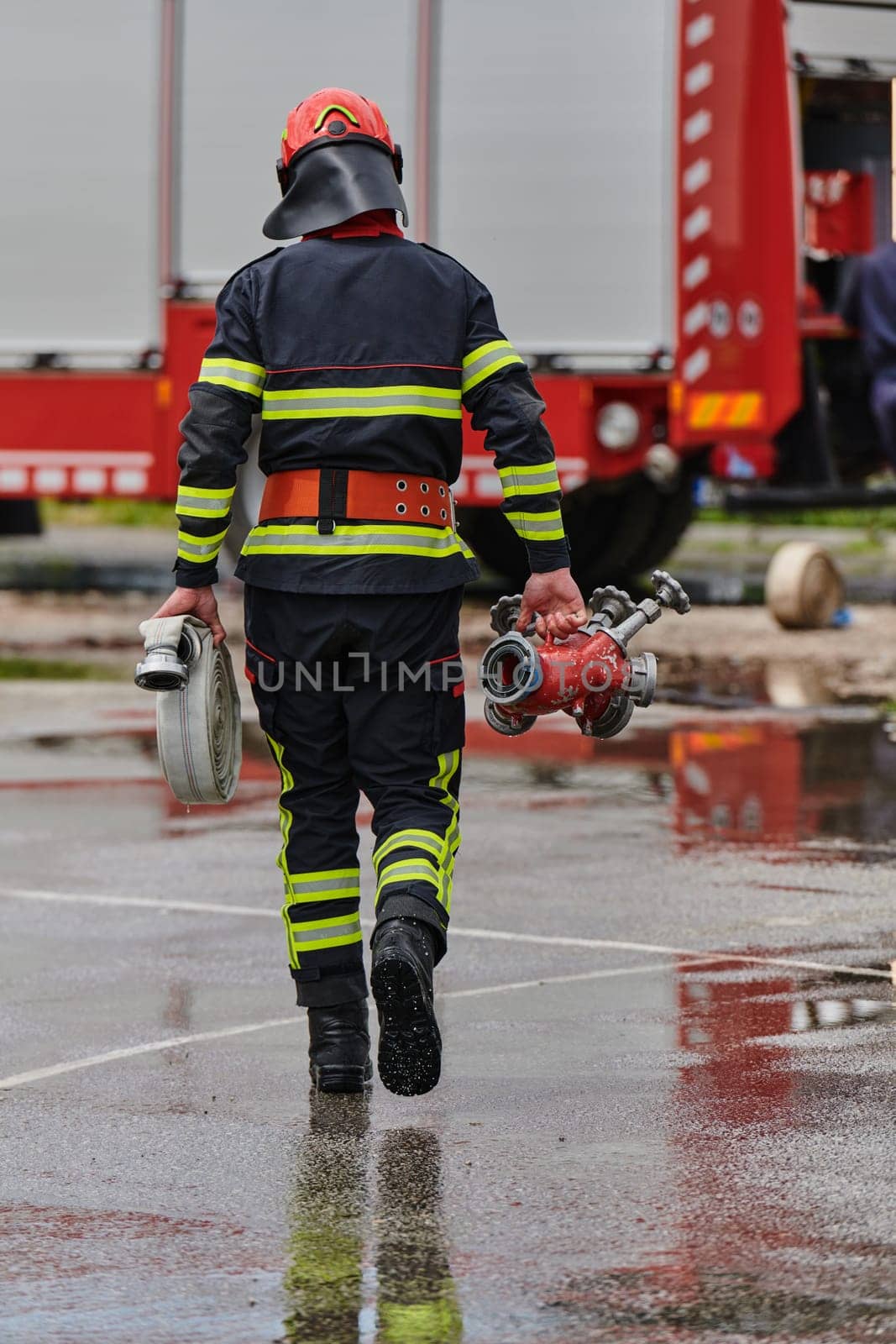 In a dynamic display of synchronized teamwork, firefighters hustle to carry, connect, and deploy firefighting hoses with precision, showcasing their intensive training and readiness for challenging and high-risk situations ahead.