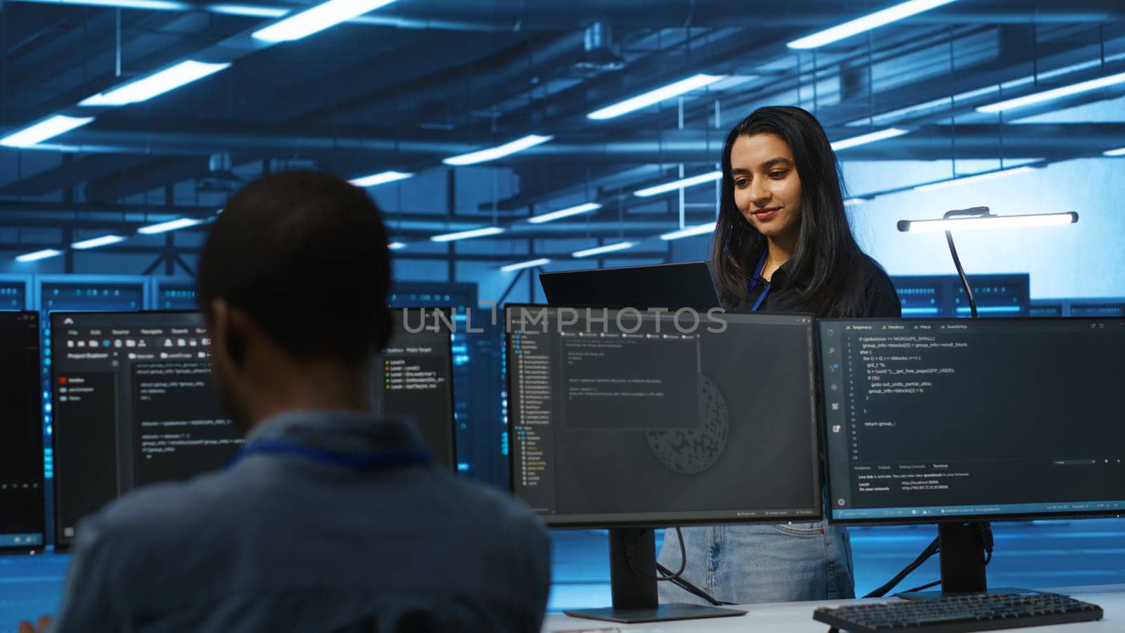 Cheerful supervisor in server room managing multiethnic team of technicians looking for equipment misconfigurations. Upbeat team leader coordinating workers fixing data center malfunctions