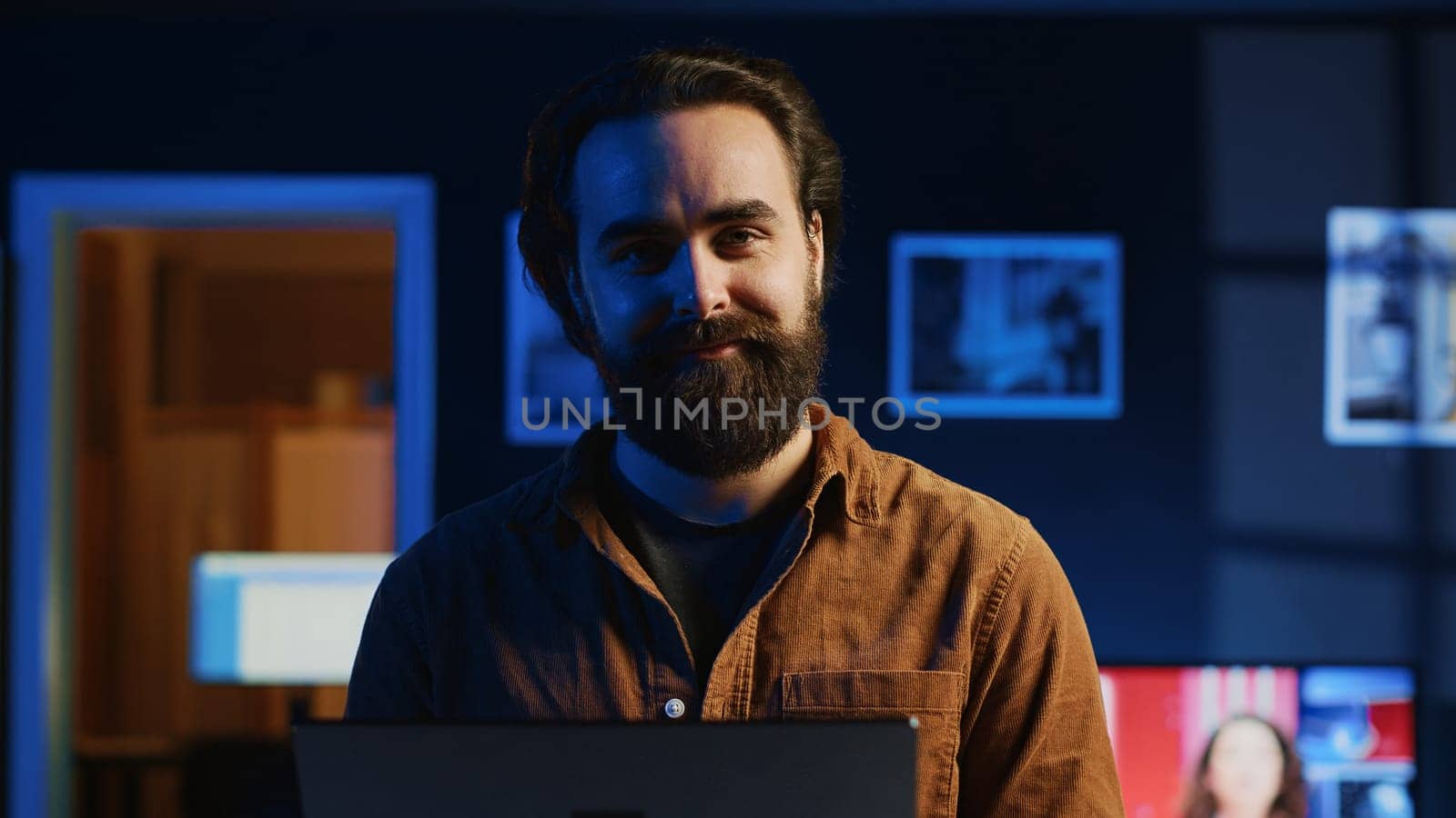Portrait of happy man doing IT support job from apartment, standing in personal office with laptop in hand, coding. Joyful developer writing lines of code on notebook, camera A close up shot