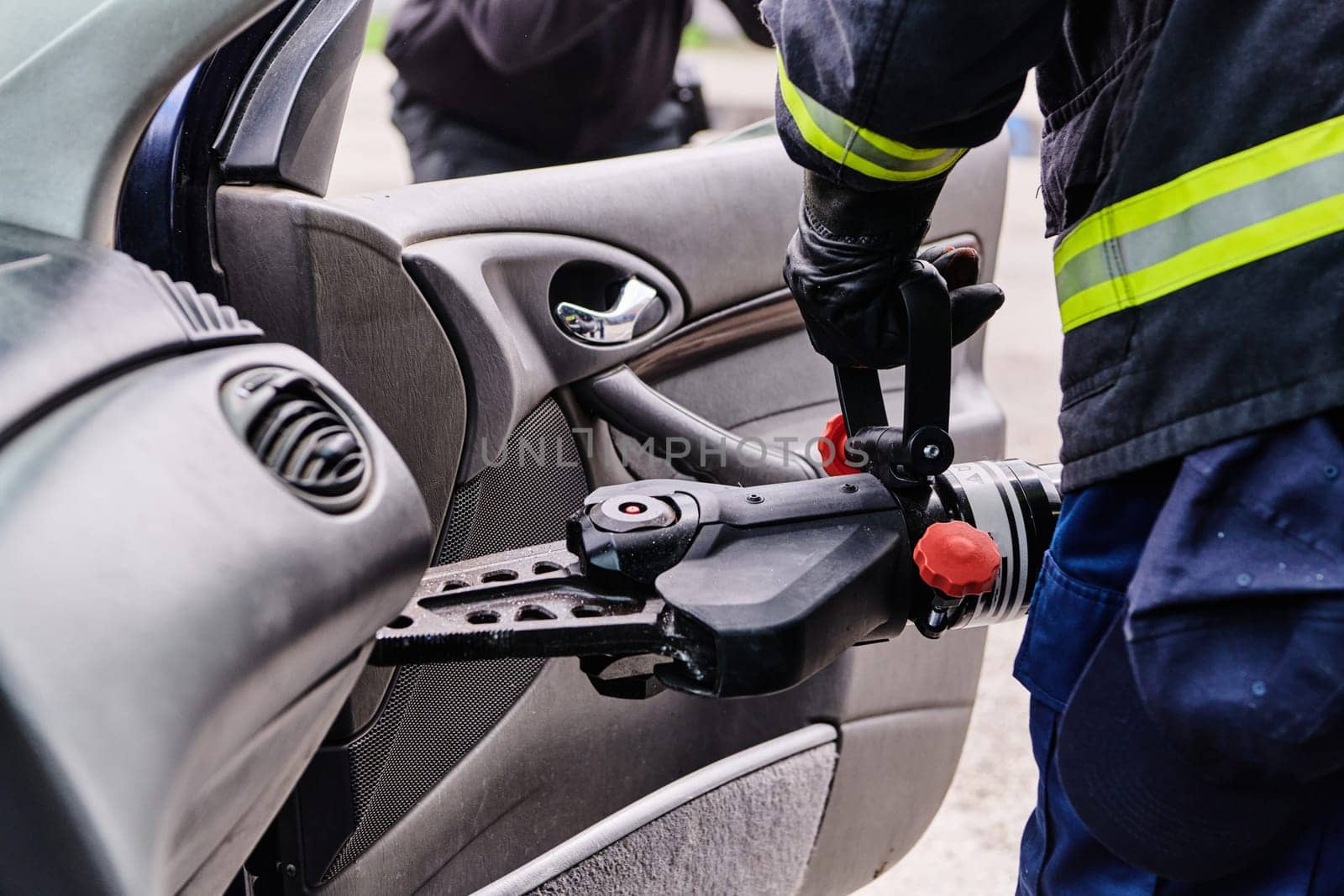 A dedicated team of professional firefighters employs specialized tools to cut and break through vehicle wreckage, showcasing their skilled collaboration and swift response in rescuing individuals involved in a car accident.