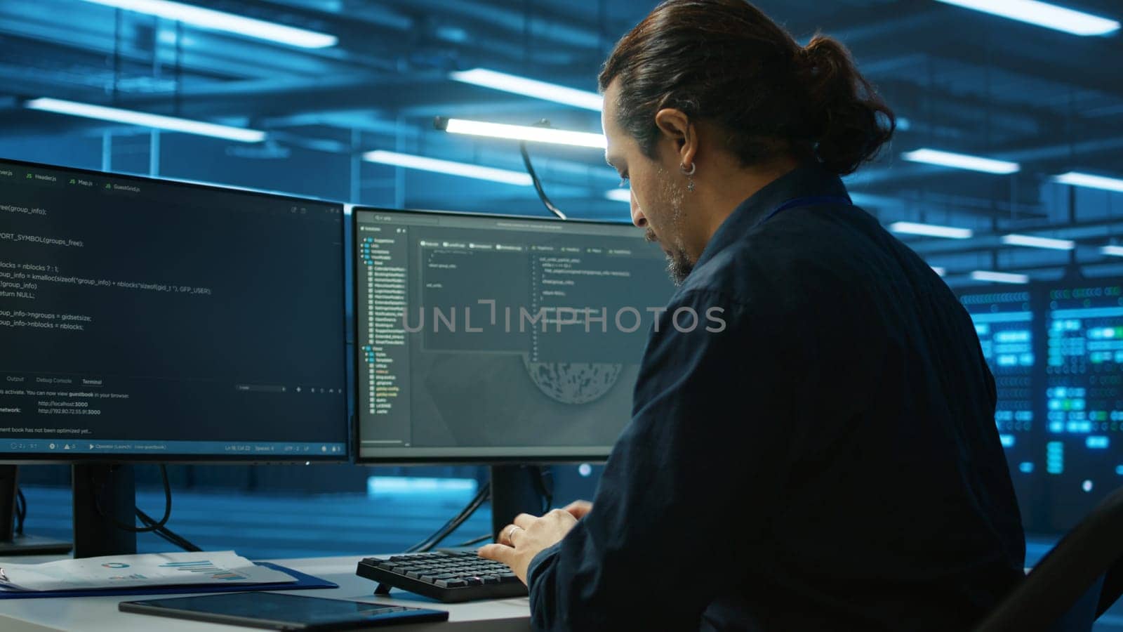 System admin focused on programming in server room housing advanced equipment storing massive datasets. Developer typing code on PC to mend data center racks doing complex computational operations