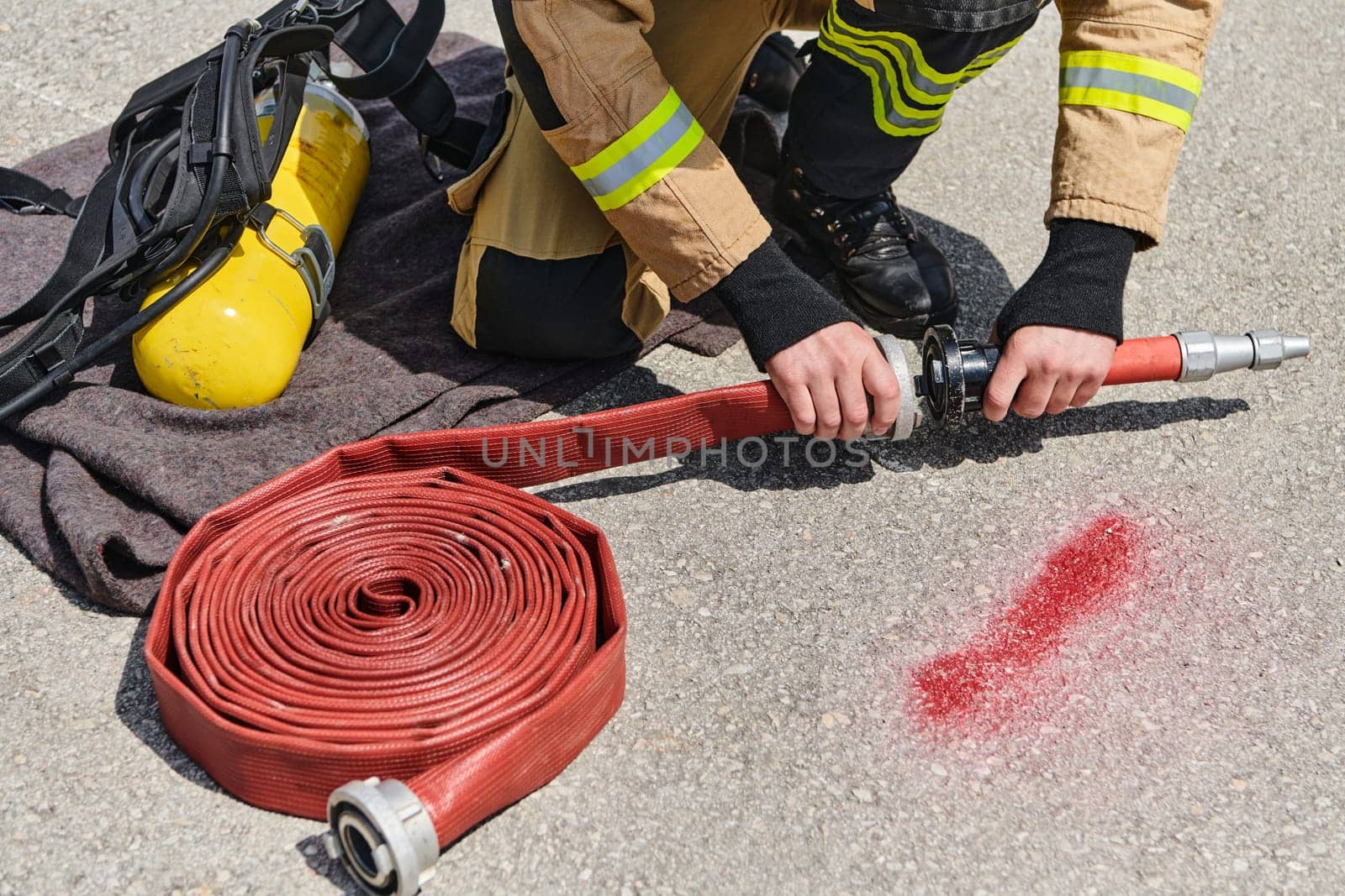 A dedicated firefighter meticulously coils the fire hose after successfully extinguishing a blaze, showcasing the critical post-incident responsibilities.