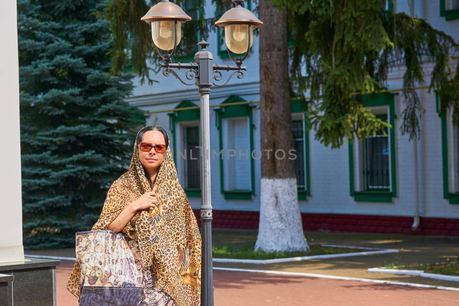 A woman in a headscarf and sunglasses on an excursion in a monastery by jovani68