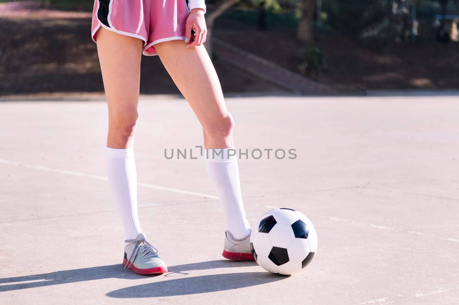 legs of an unrecognizable woman next to a soccer ball ready to play in a urban football court, concept of sport and active lifestyle