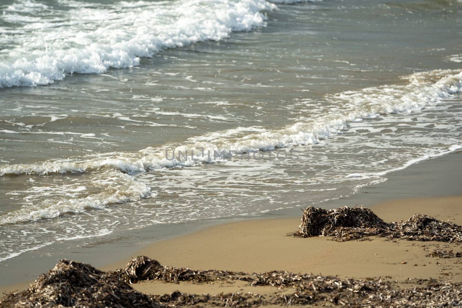 View from below of sandy beach and waves at sunset by Sonat