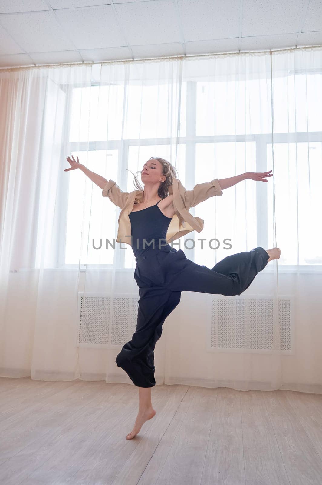 Caucasian woman dances contemporary in ballet class. Dancer in a jump. Vertical photo