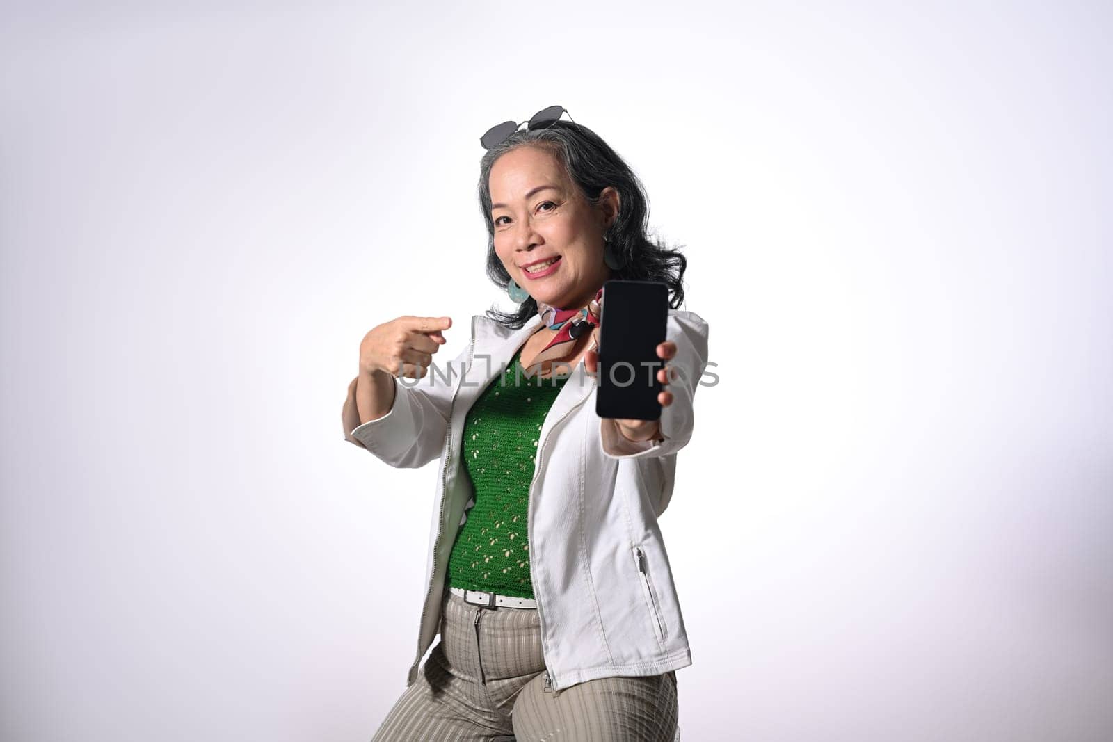 Confident middle age woman showing mobile phone isolated on white background.