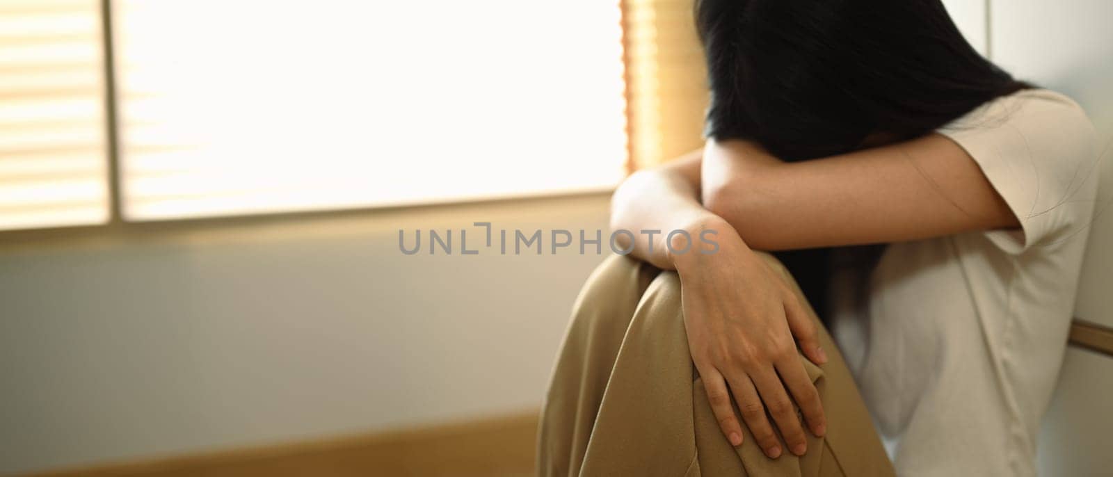 Upset distressed young woman sitting on floor at home. Psychological and mental health concept.