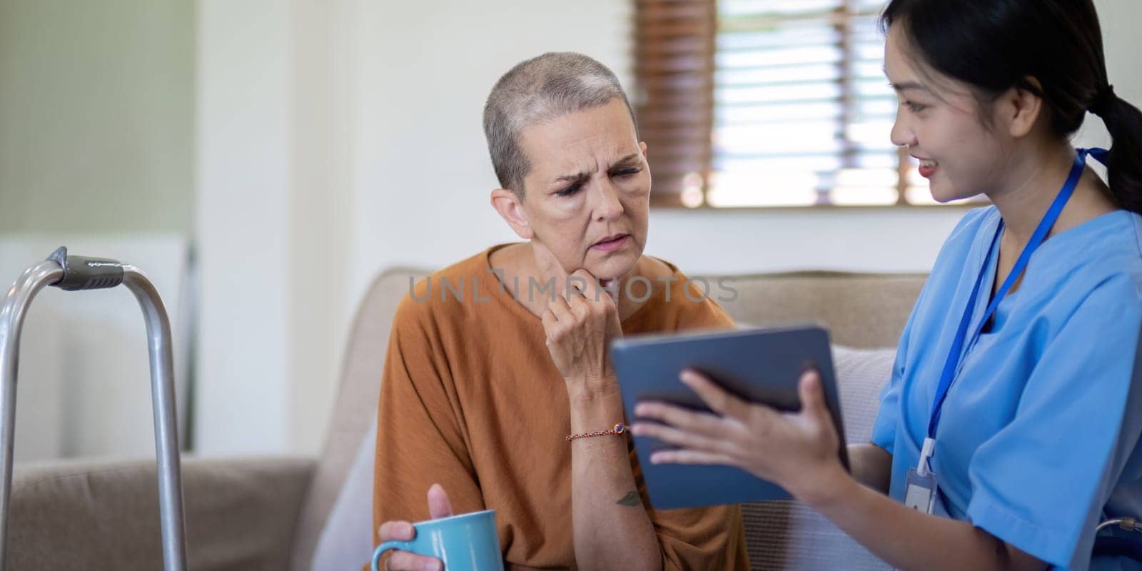 Asian caregiver discussing health information with an elderly woman at home, emphasizing elderly care and digital health management