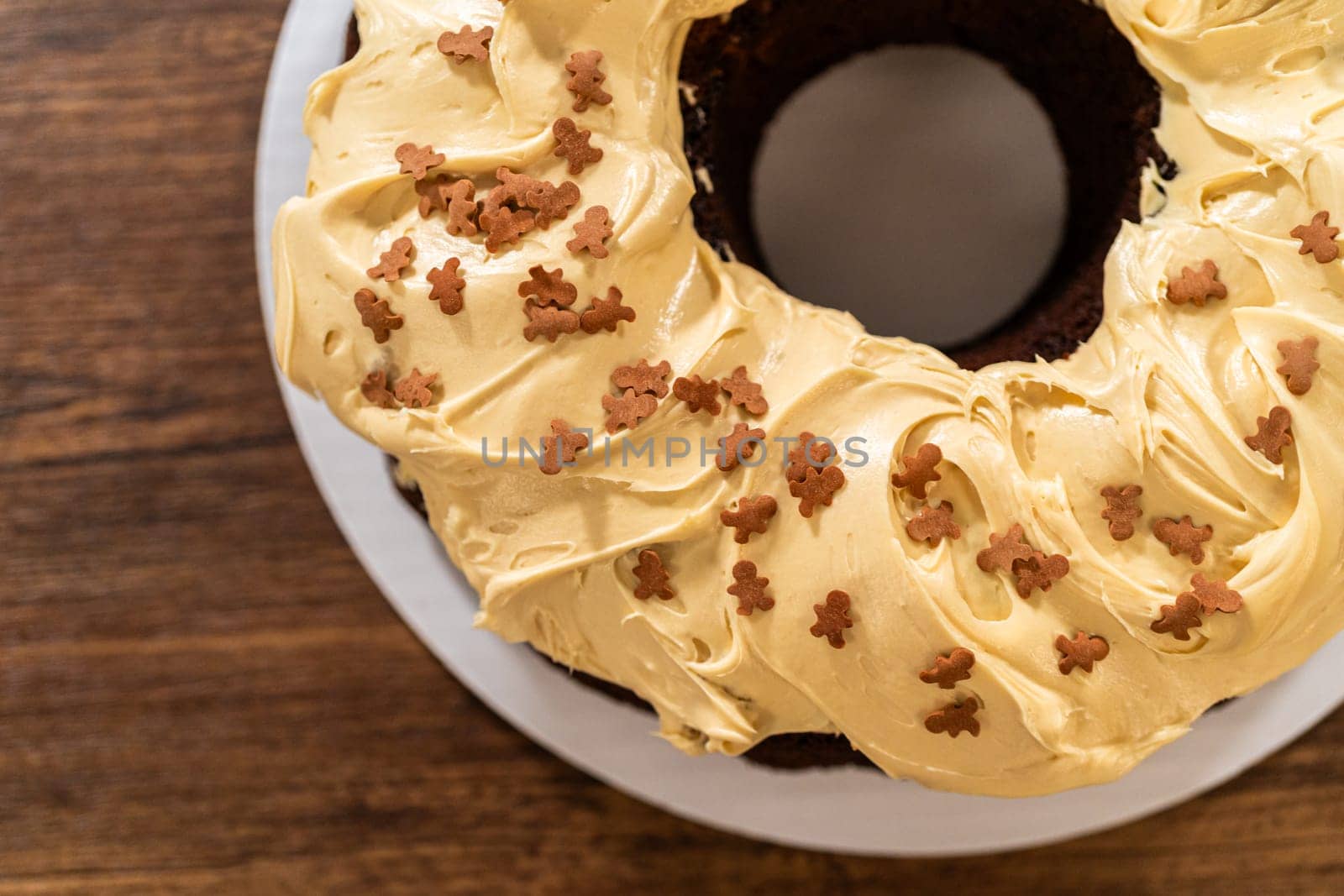 Carefully placing the gingerbread bundt cake, adorned with salted caramel frosting and gingerbread sprinkles, into a white paper bundt cake box with a clear window for gifting.