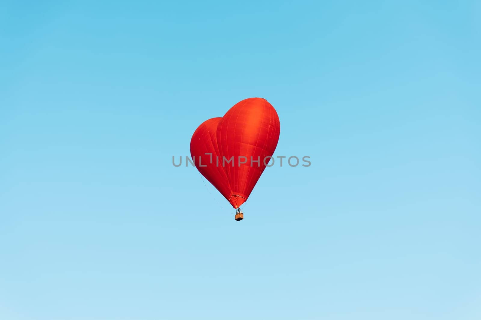 red heartshaped balloon soaring against a backdrop of clear blue sky