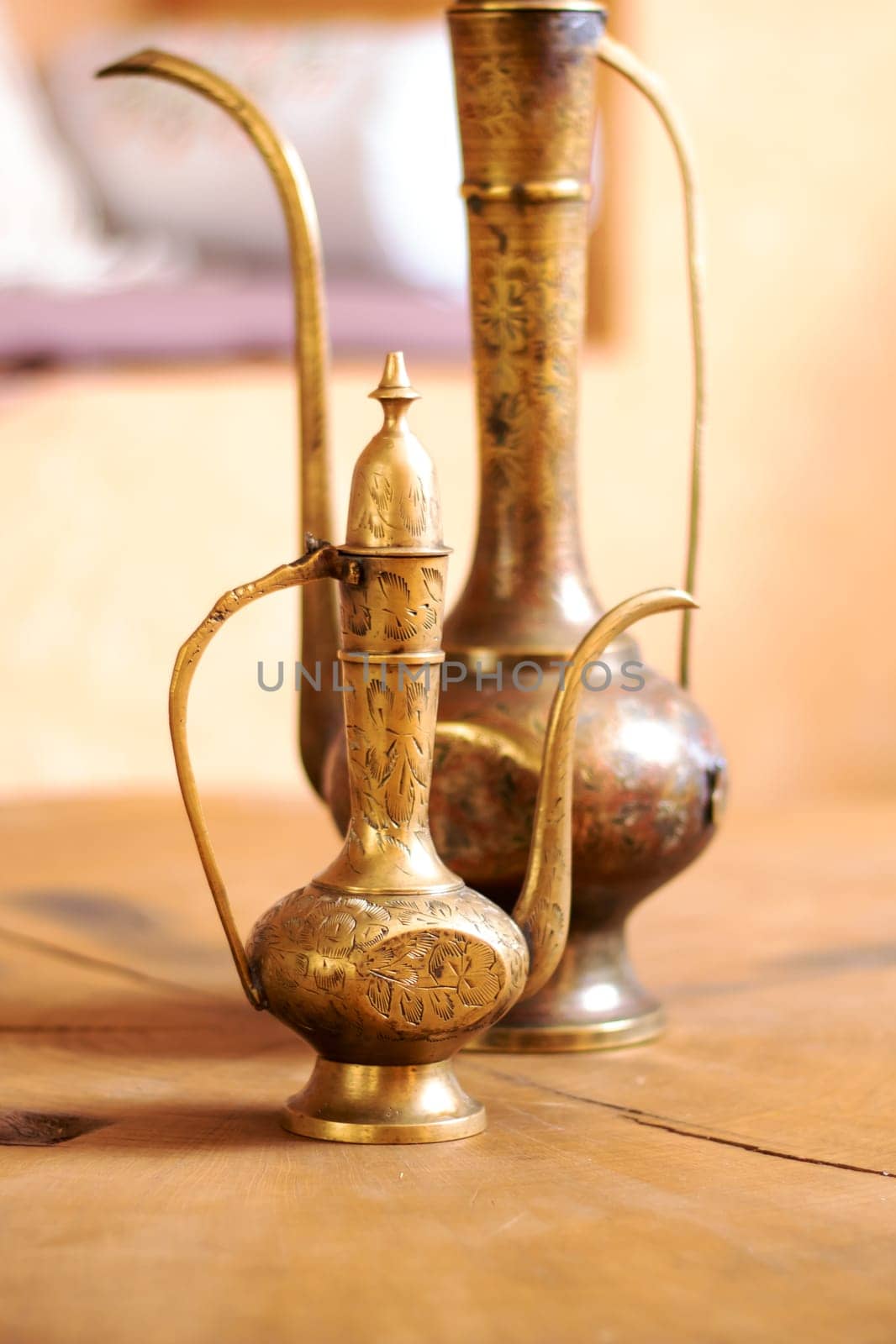 Two brass vases are elegantly placed on a rustic wooden table, creating a charming and stylish decor piece