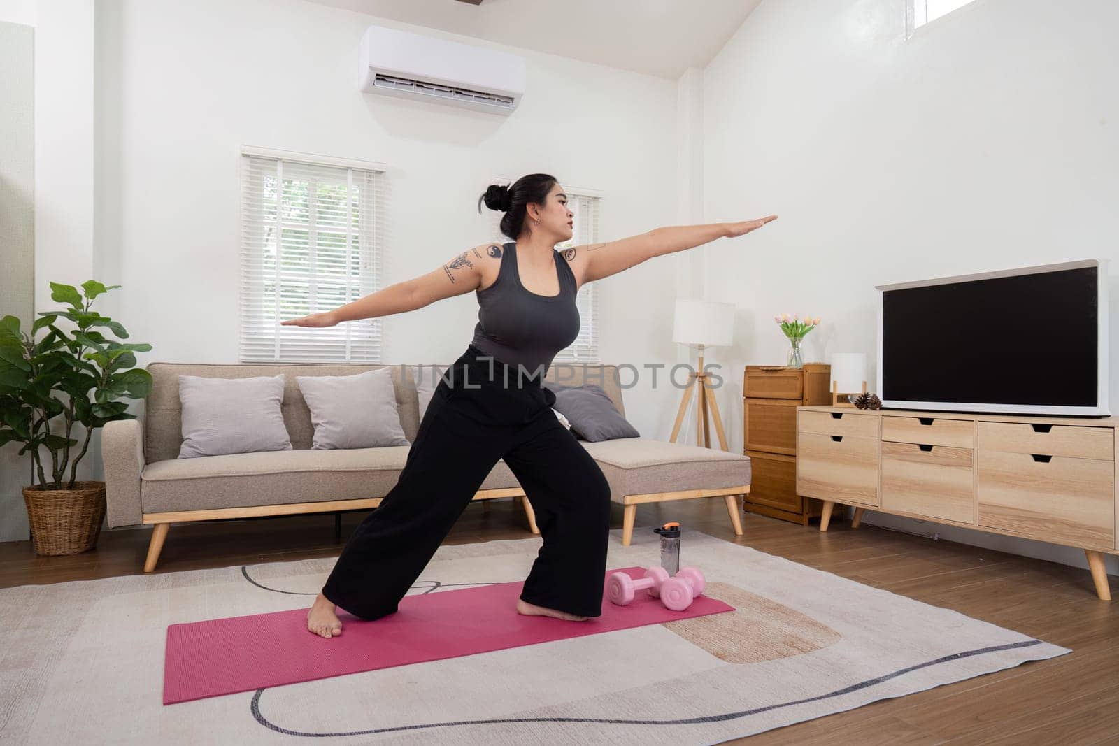 Plus-size woman practicing yoga at home, embracing a healthy lifestyle and weight loss journey in a modern living room.