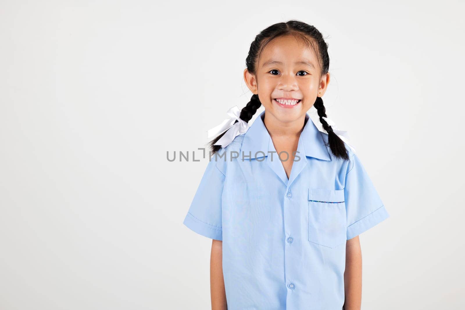 Portrait smiling Asian little girl kindergarten studio shot isolated white background, good job feedback, happy woman kid in pigtails wearing school uniform, back to school concept