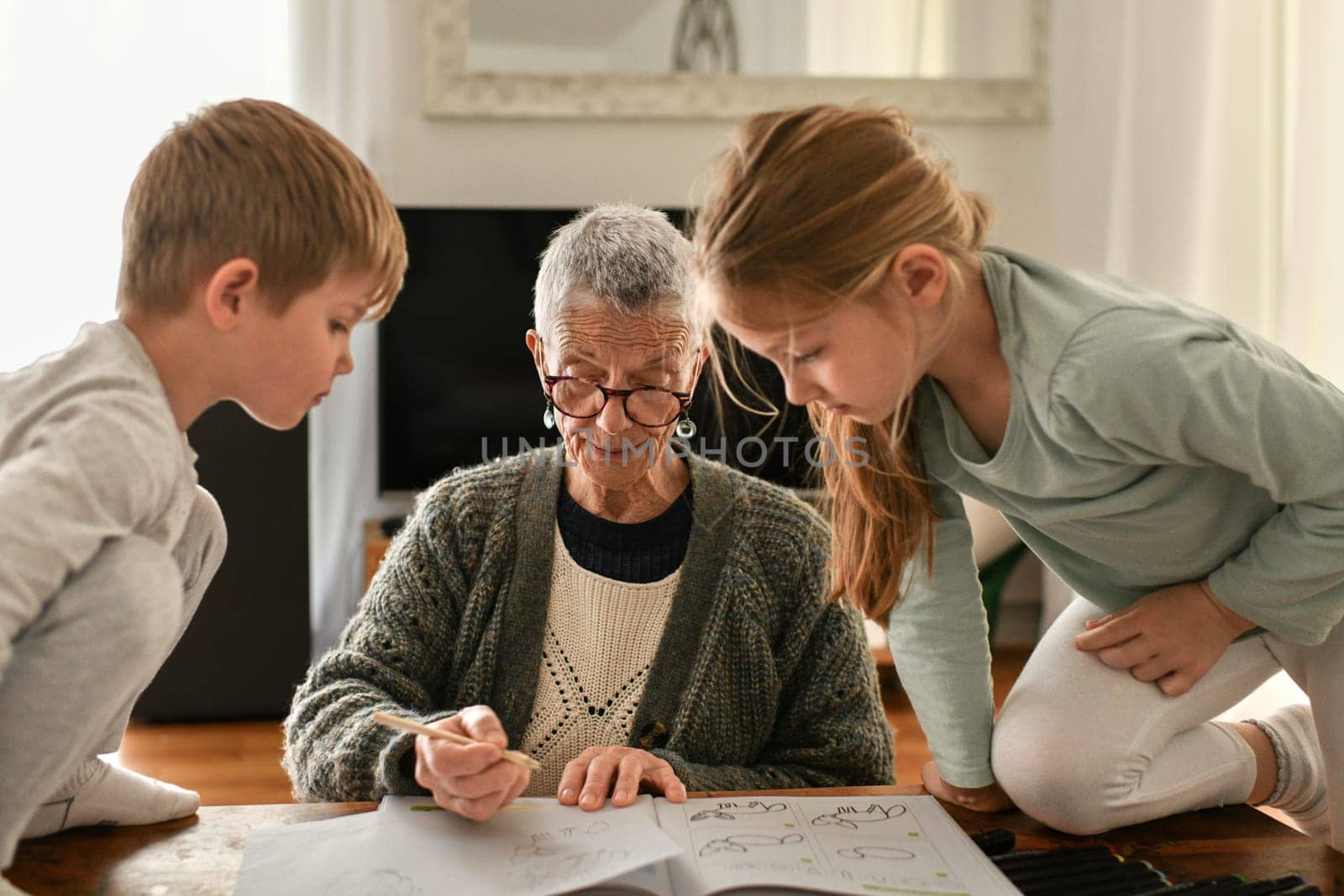 Gray-haired grandmother plays with her little grandchildren in a flat