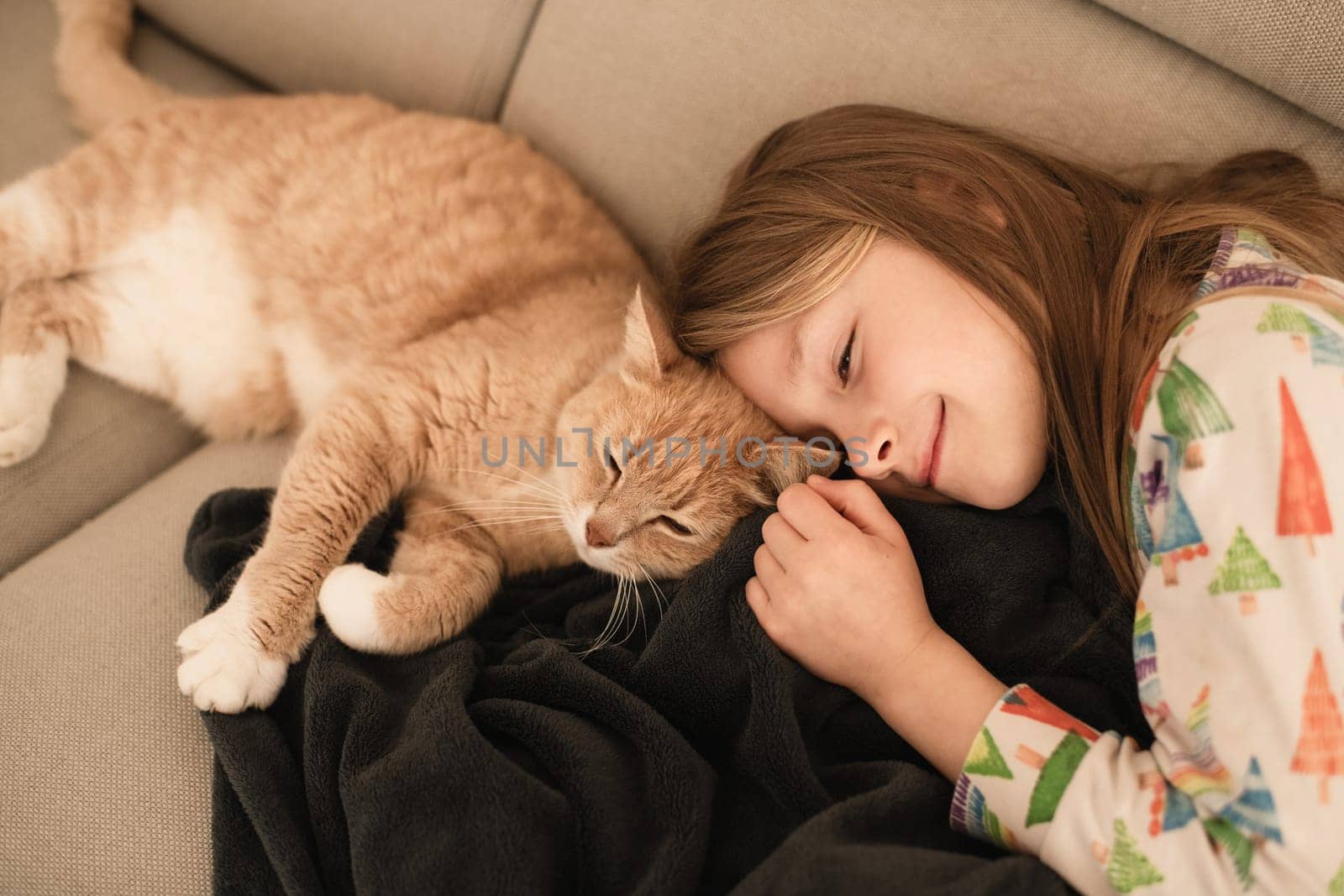 A girl near a ginger cat on the sofa