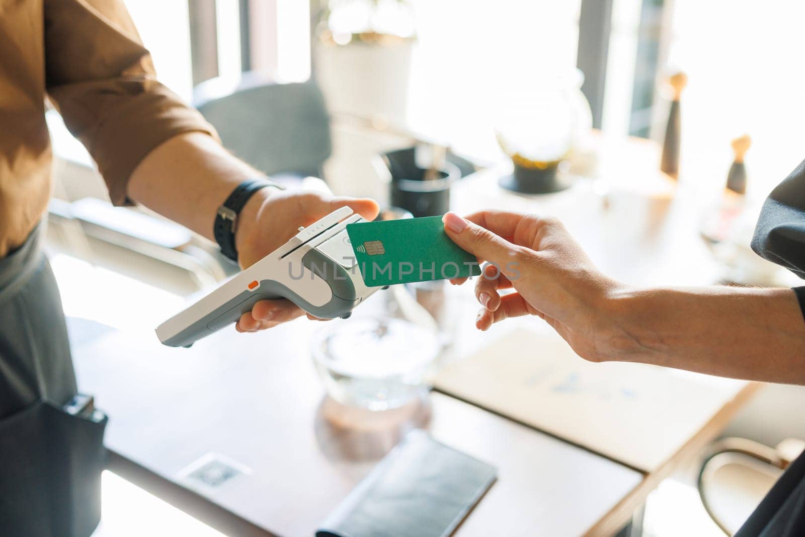 NFC credit card payment. Woman paying with contactless credit card with NFC technology. Wireless money transaction. Card machine in male hand on sunlight background