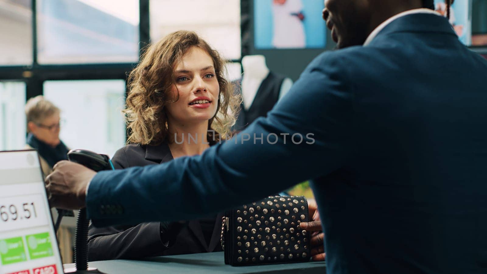 Trendy woman prepared to buy designer bag at store checkout by DCStudio