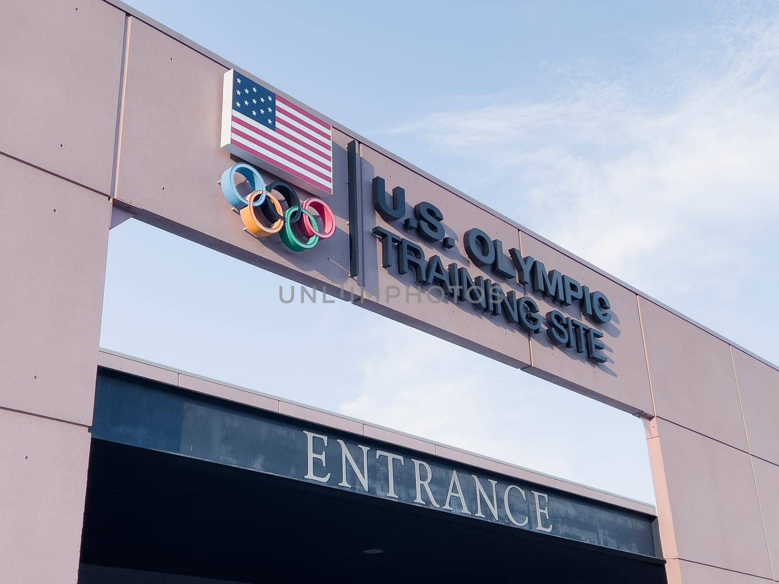 Colorado Springs, Colorado, USA-May 13, 2024-A detailed shot of the entrance sign for the U.S. Olympic Training Site, featuring the American flag and Olympic rings under a clear sky.