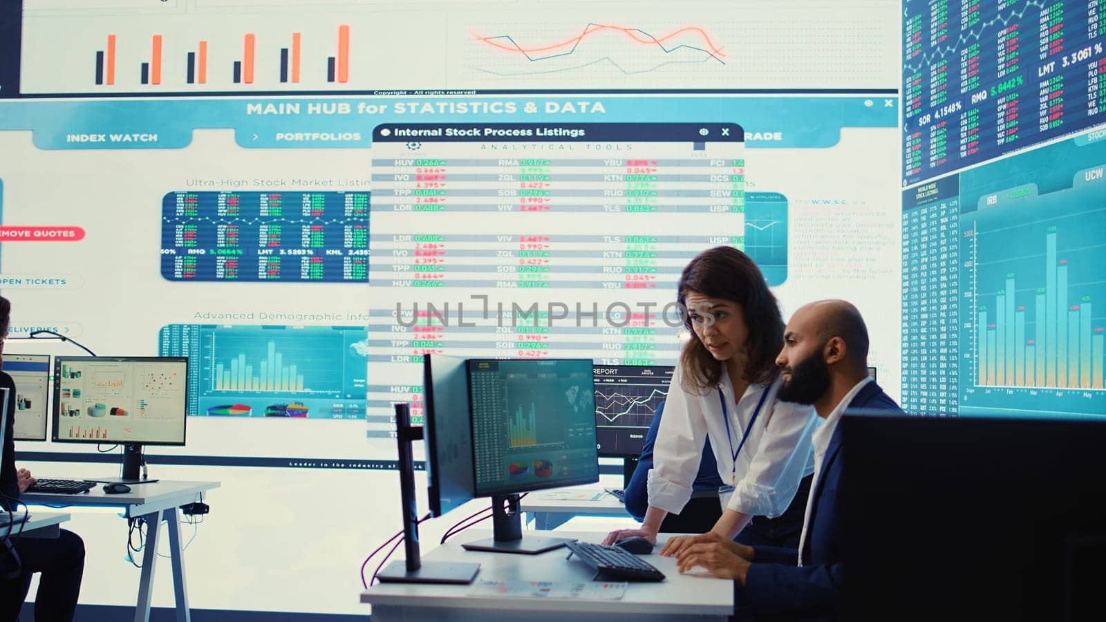 Teammates examining statistics and infographics on computer in control room by DCStudio