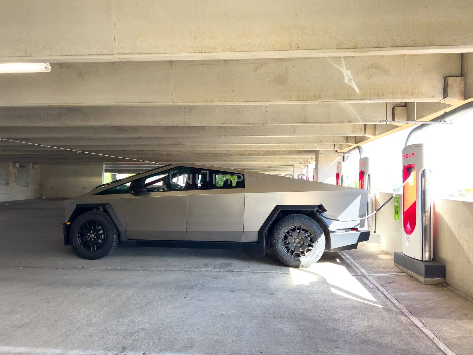 Denver, Colorado, USA-May 31, 2024-A Tesla Cybertruck parked in an indoor charging station, showcasing its futuristic design and rugged build. The setting highlights the vehicles presence in a modern, urban environment.