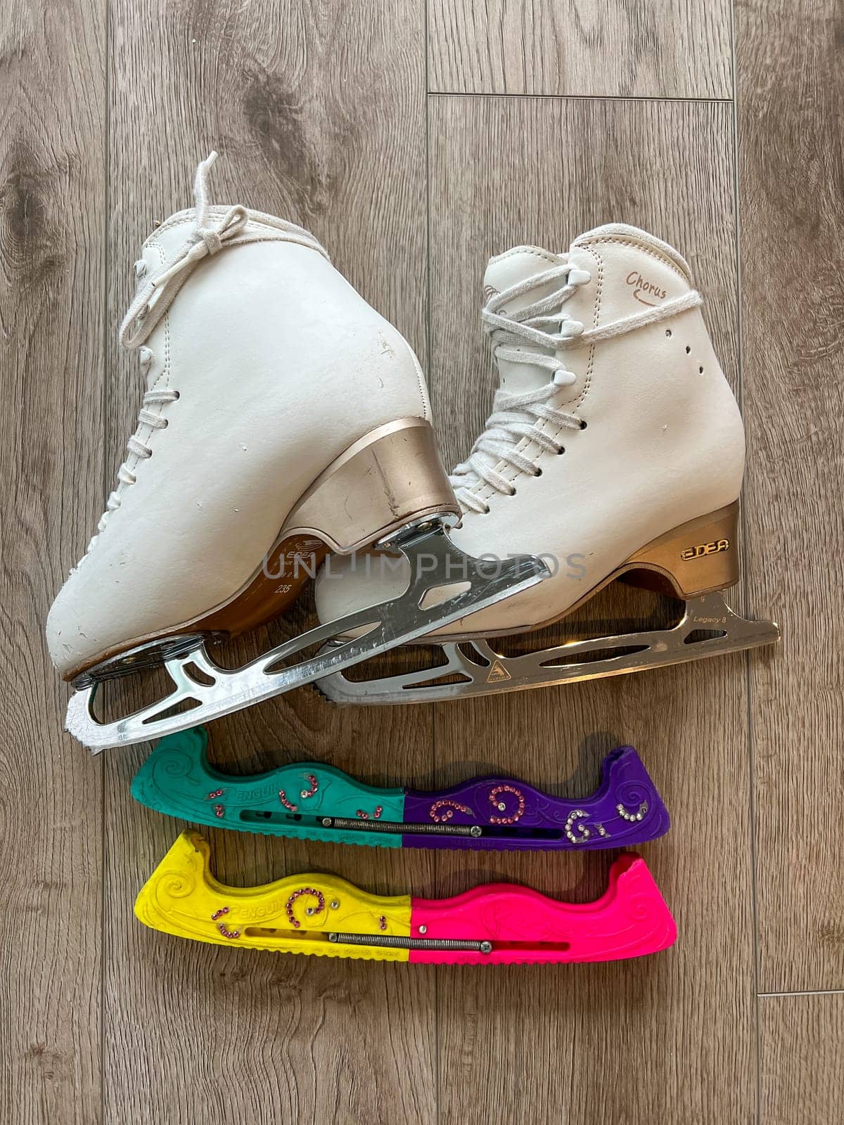 Denver, Colorado, USA-April 20, 2024-A close-up shot of a pair of white ice skates with gold accents, placed on a wooden floor. The skates show signs of use, adding character to the image.