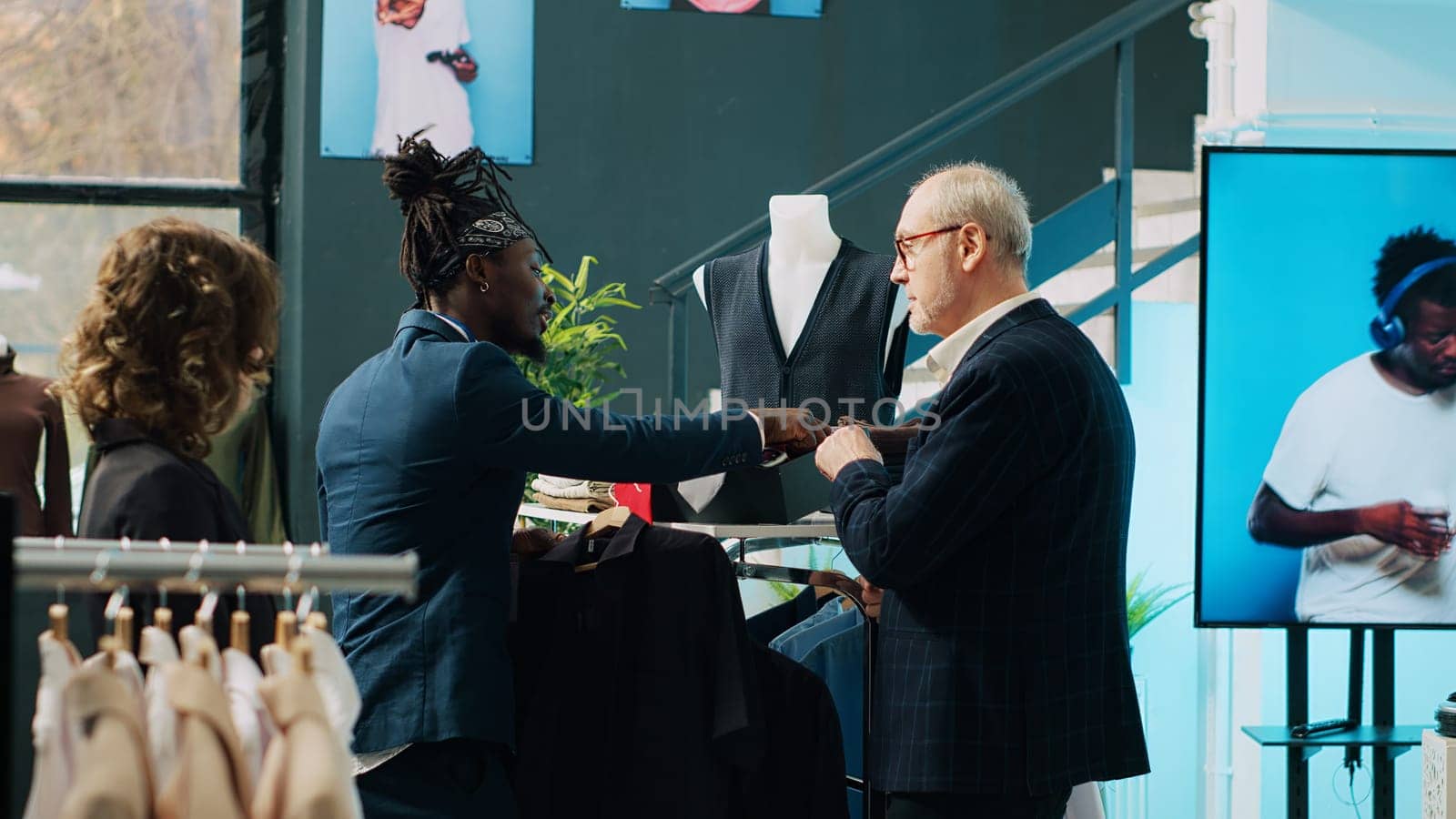 African american store assistant helping old customer to match tie with a shirt by DCStudio