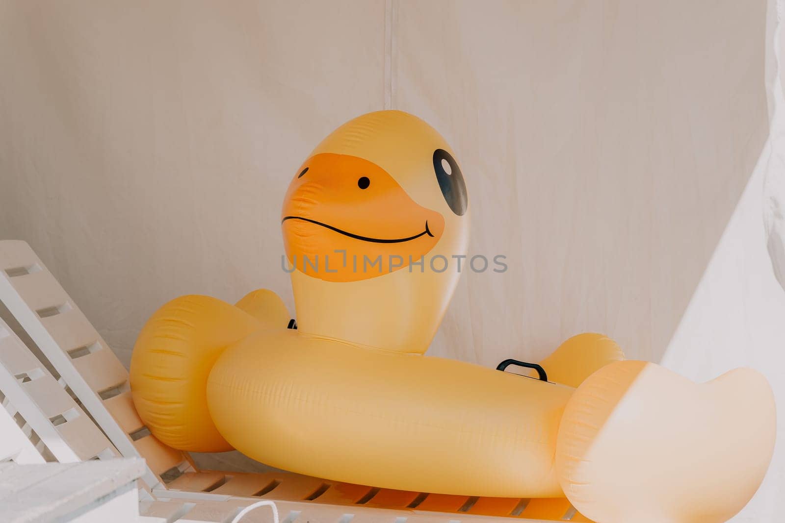 Inflatable duckling, pool, summer - Bright yellow floatation device enhances swimming experience for children during warm days.