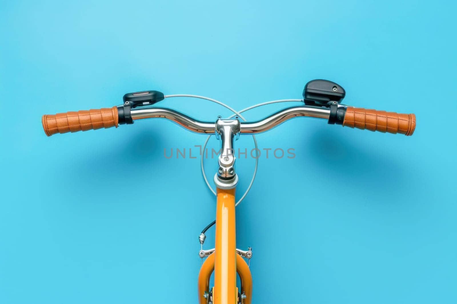 In the image, there is the front of a yellow bicycle with brown handlebars against a blue background