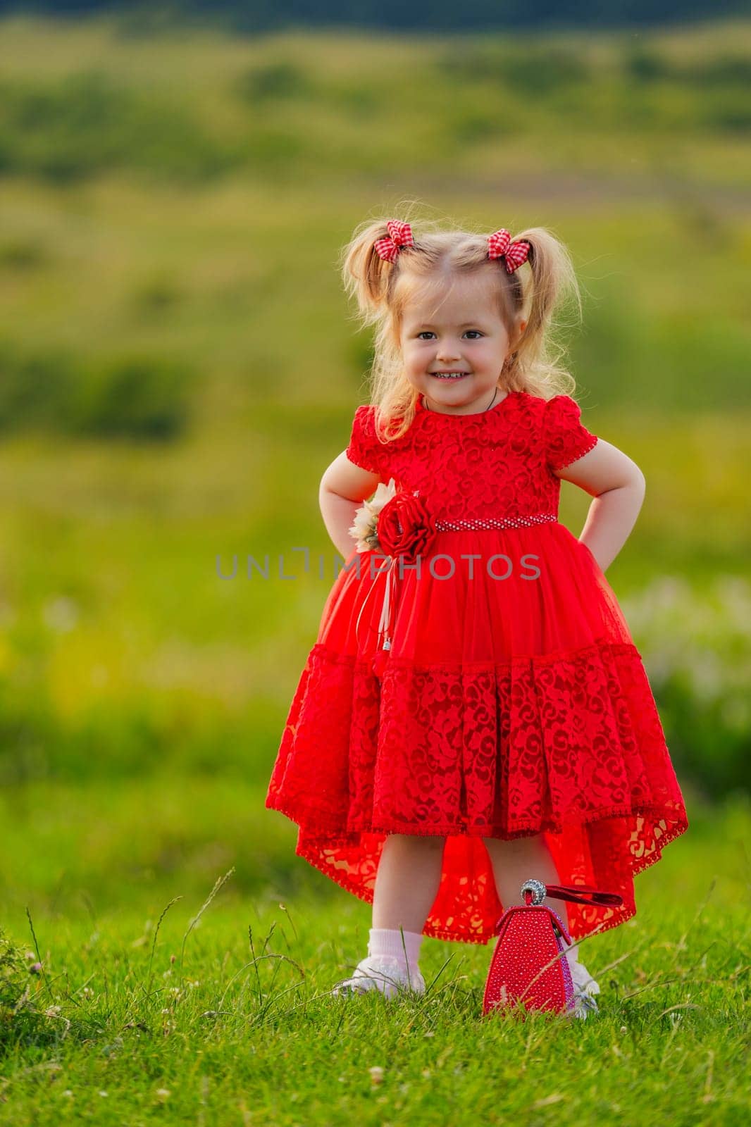 little girl in a red dress walks on the lawn