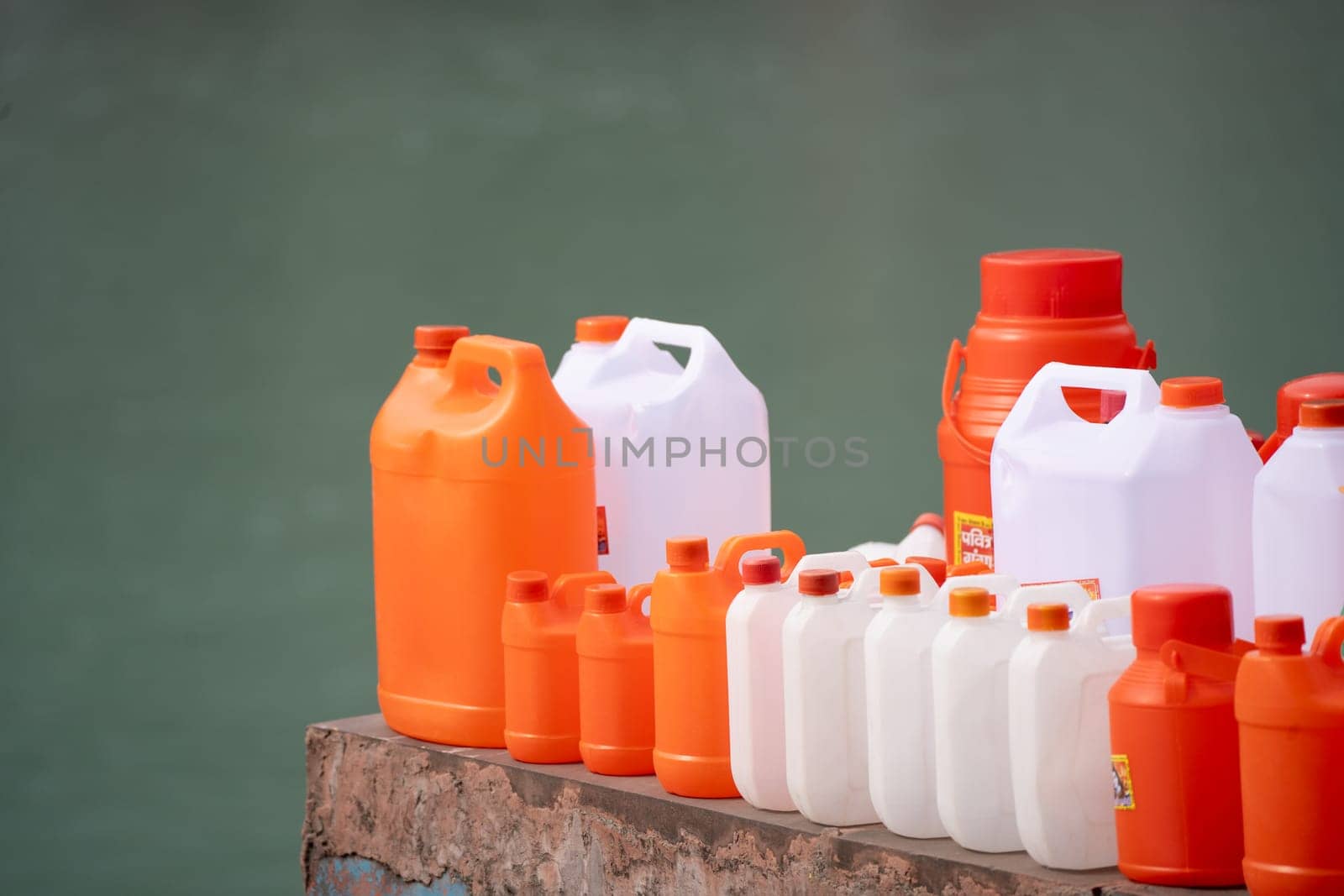 colorful plastic cans in orange saffron and white showing the traditional vessels used to fill holy water from ganga river to take home in India