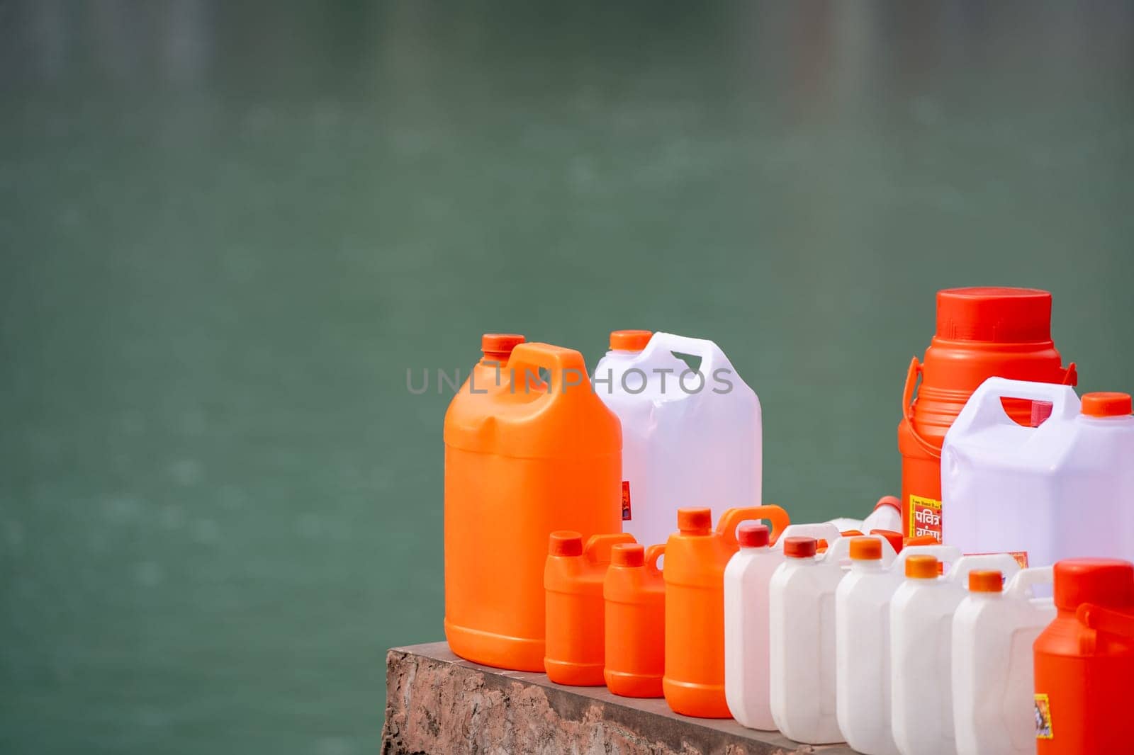 colorful plastic cans in orange saffron and white showing the traditional vessels used to fill holy water from ganga river to take home in India