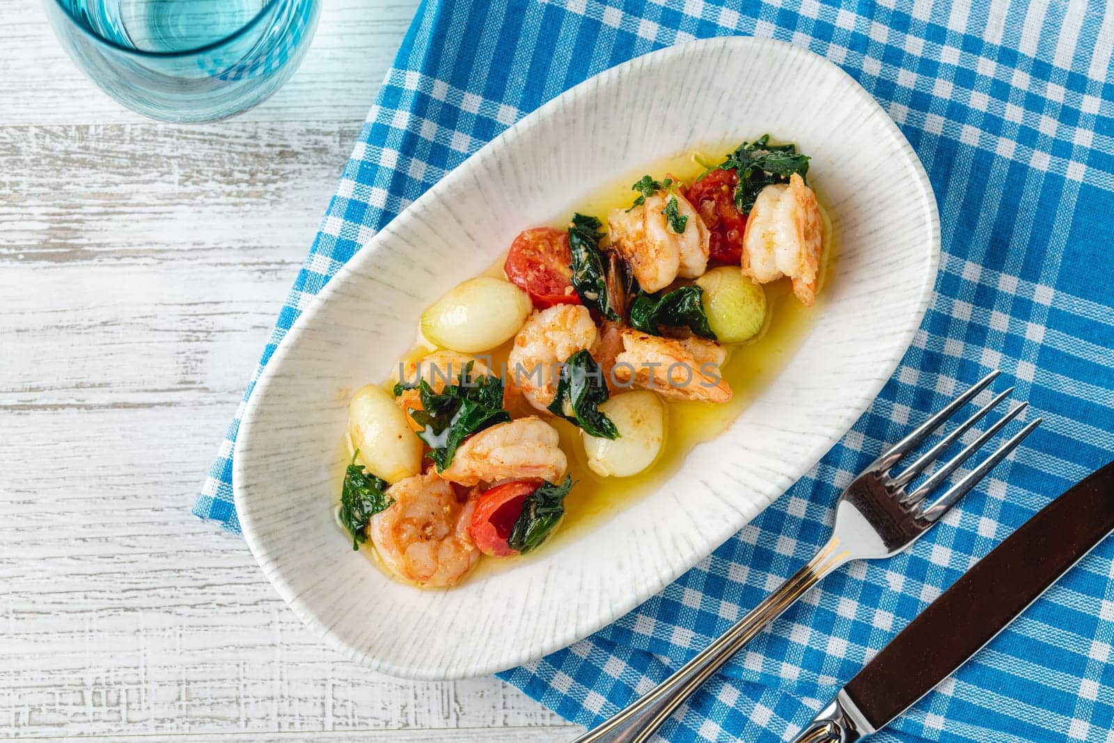 Appetizer with shrimps, onions and tomatoes on a white porcelain plate