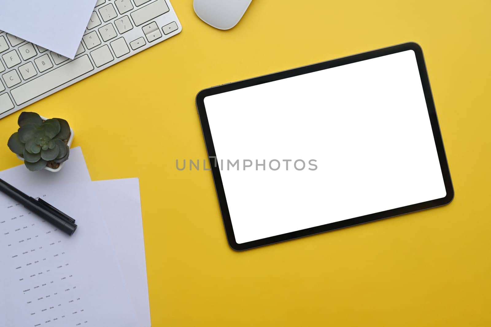 Digital tablet on yellow background with keyboard and potted plant by prathanchorruangsak