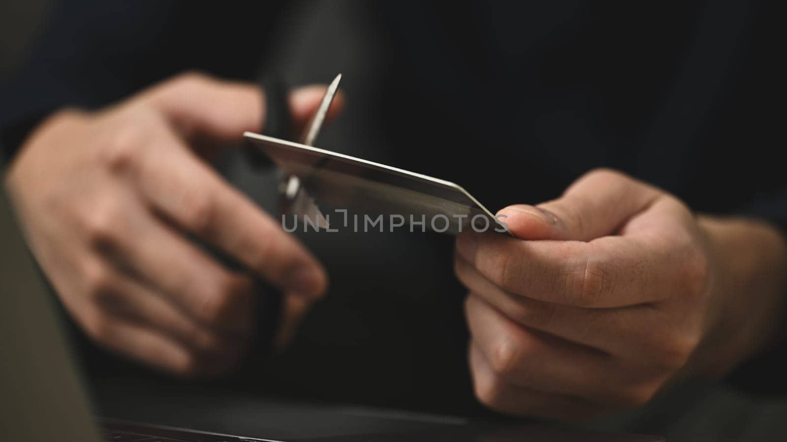 Young man cutting credit card with scissors. Financial problems concept.