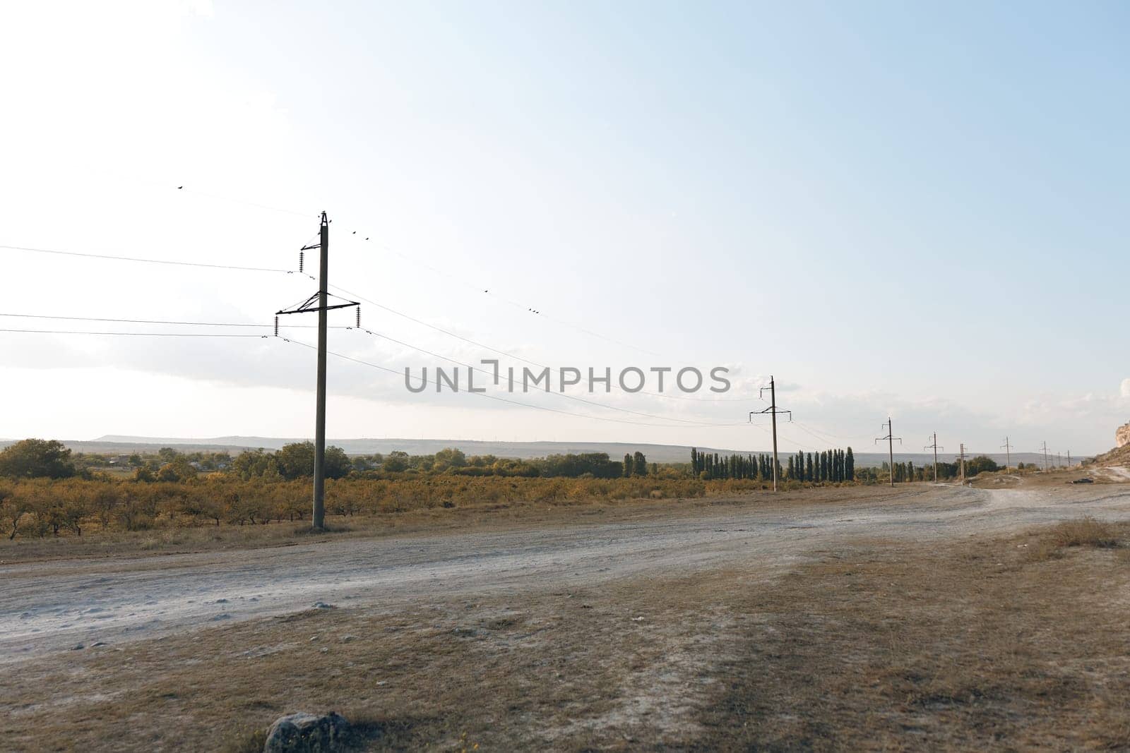 Rural landscape with winding dirt road and power lines stretching into the distance