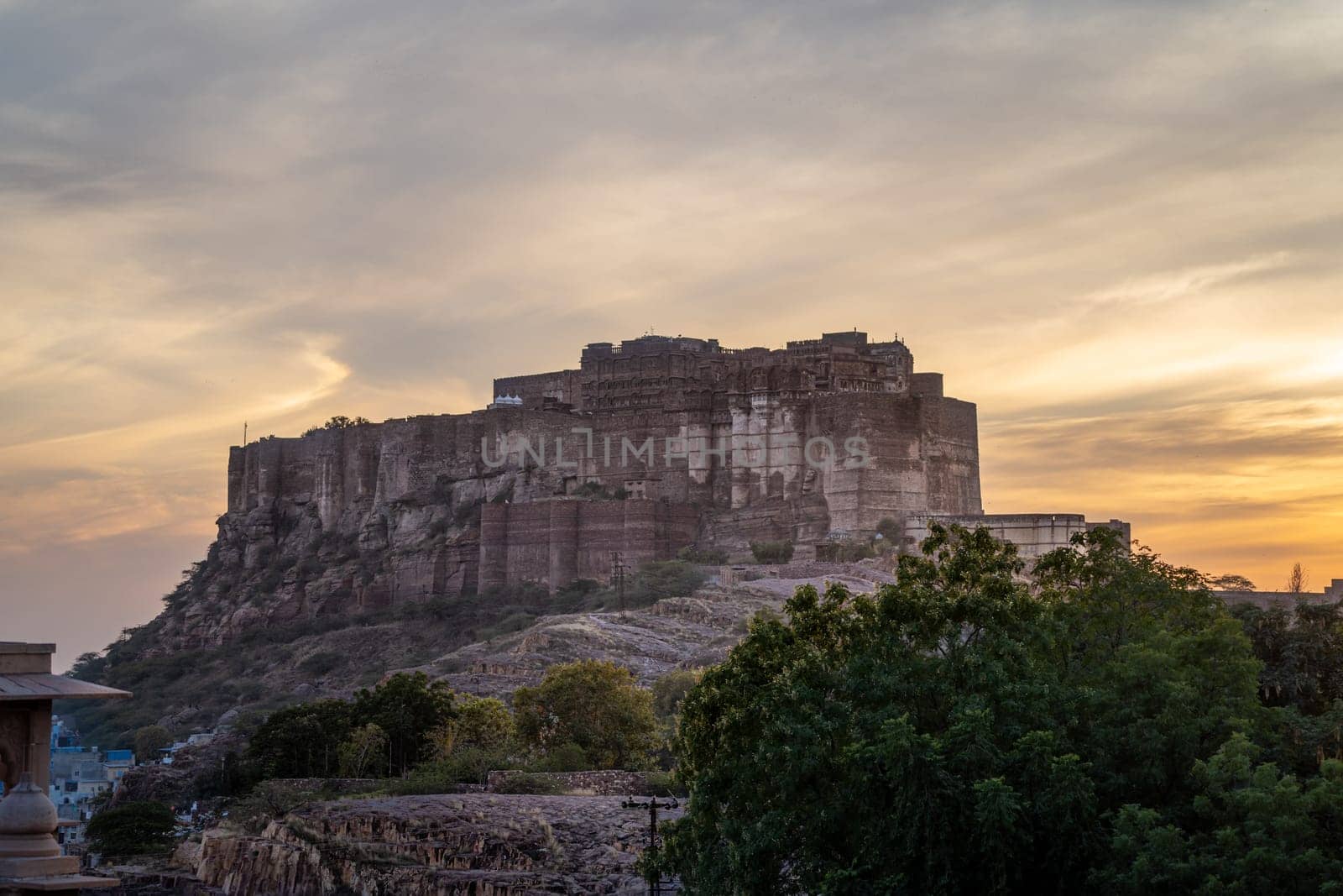 mehrangarh fort in Jodhpur Rajasthan sitting on hilltop surrounded by orange monsoon clouds showing the landmark in India