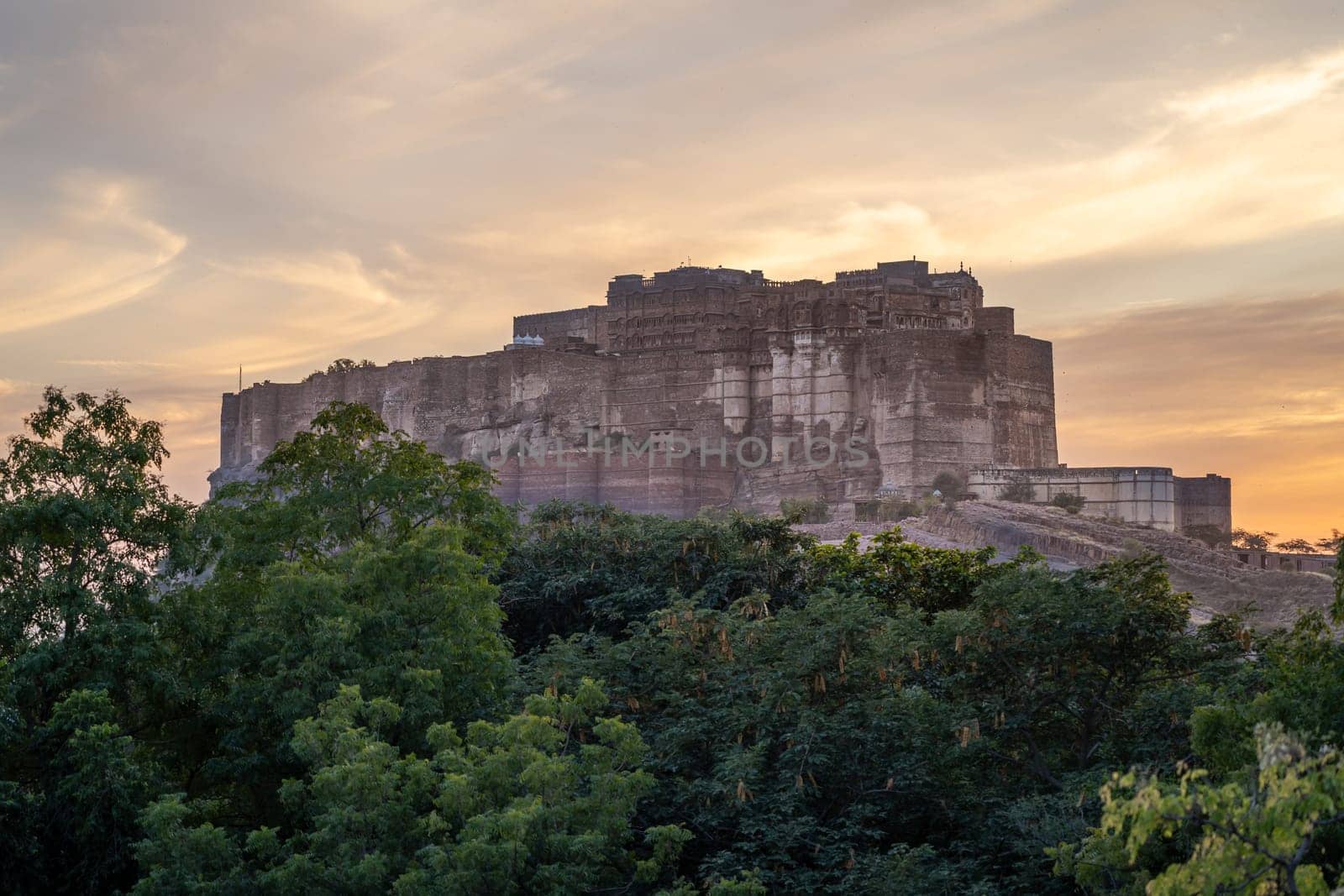 mehrangarh fort in Jodhpur Rajasthan sitting on hilltop surrounded by orange monsoon clouds showing the landmark in India