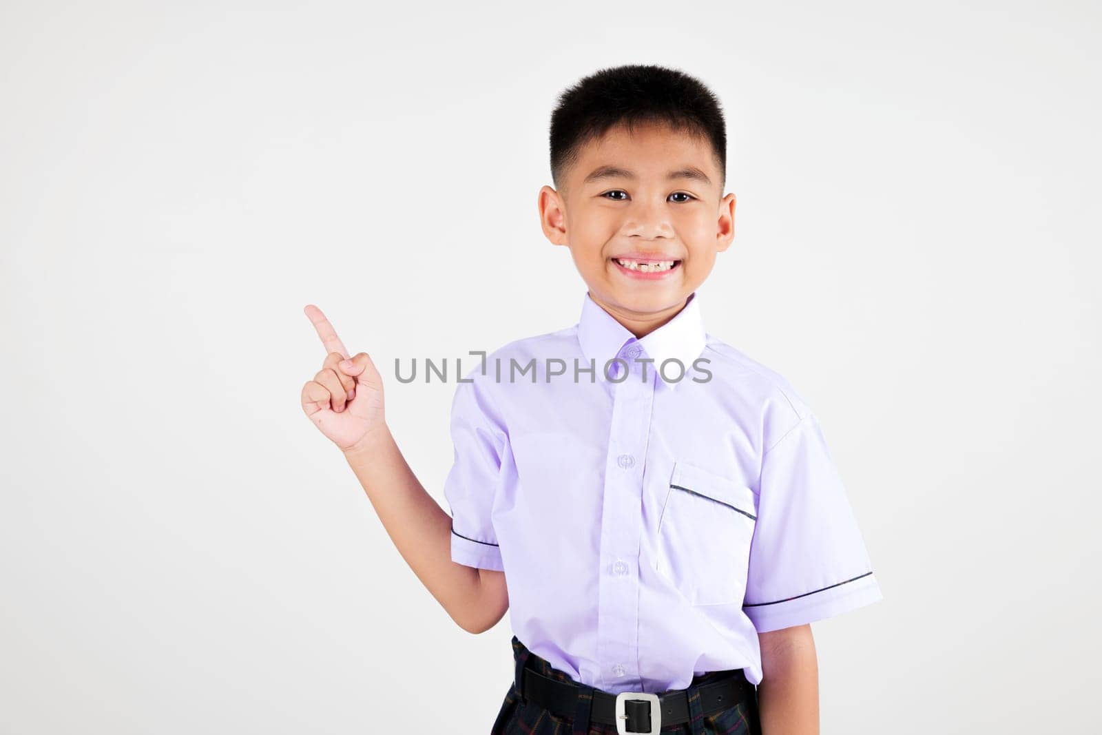 Portrait smile Asian little boy primary posing point finger to side away studio isolated white background, happy cute man kid wear school uniform plaid innocence and curiosity, back to school concept